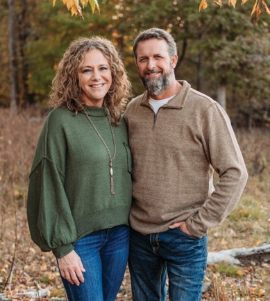 Photo of a smiling couple standing in a rustic autumn scene after losing weight following the Eat to Lose program